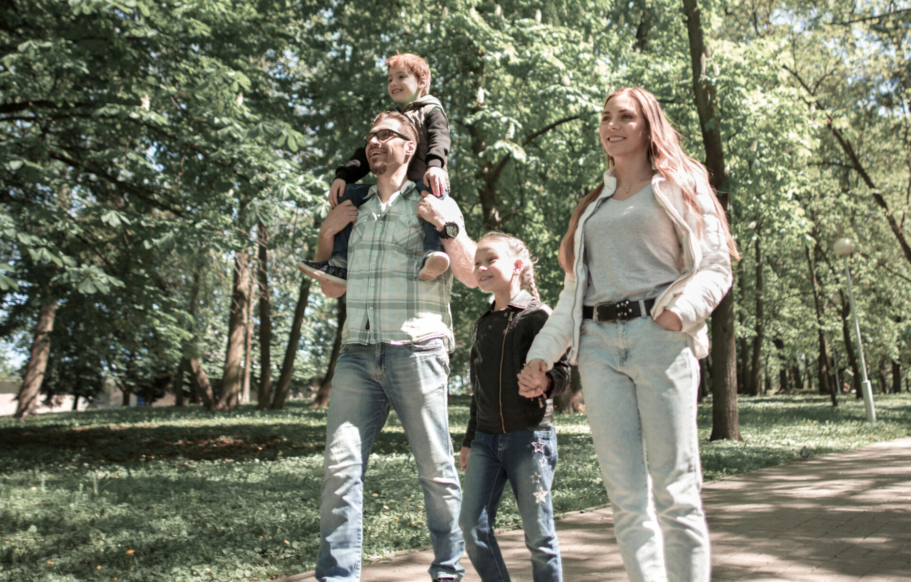 Family Enjoys A Walk In The City Park.