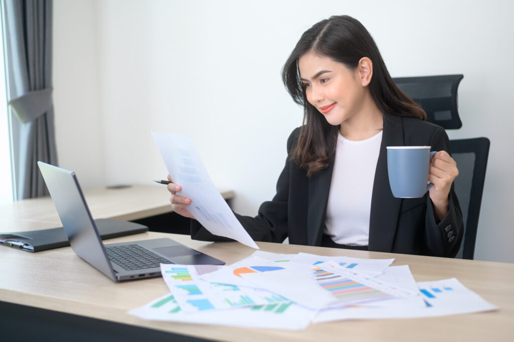Young Beautiful Business Woman Working On Laptop With Documents In Modern Office